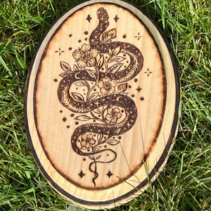 May include: A wooden tray with a woodburned design of a snake wrapped around flowers and stars.