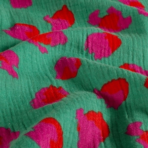 gros plan sur le motif léopard de ce tissu en gaze de coton vert. on peut voir que le tissu est légèrement texturé