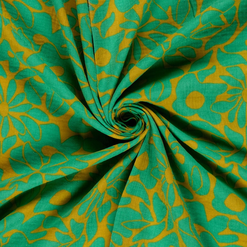 May include: Close-up of a fabric with a repeating floral pattern. The design features large, stylized flowers in shades of green and gold. The fabric is gathered, creating a swirling effect that highlights the pattern's details. The overall aesthetic is vibrant and eye-catching.