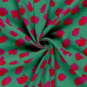 tomber du tissu en gaze de coton vert à motif léopard rouge et rose. ce tissu est parfait pour des vêtements d'été ou des accessoires matelassés.