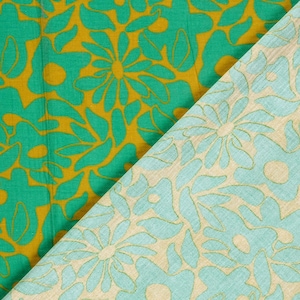 May include: A textile fabric featuring two distinct sections. One side displays a vibrant green floral pattern on a mustard yellow background, while the other side shows a light mint green floral pattern on a beige background.