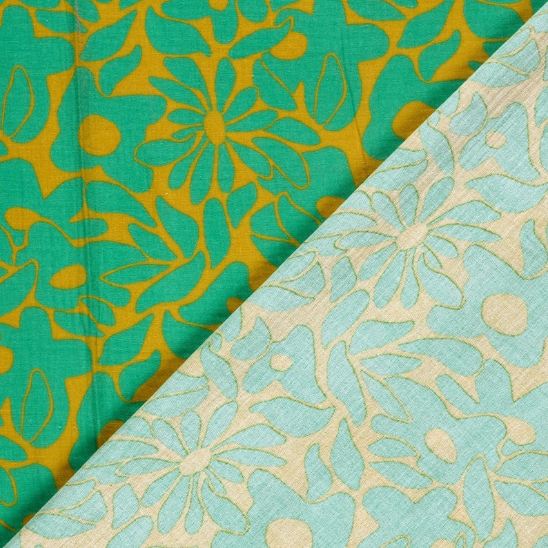 May include: A textile fabric featuring two distinct sections. One side displays a vibrant green floral pattern on a mustard yellow background, while the other side shows a light mint green floral pattern on a beige background.
