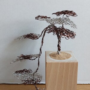 May include: A wire sculpture of a tree with silver and copper wire branches. The tree is on a wooden base.