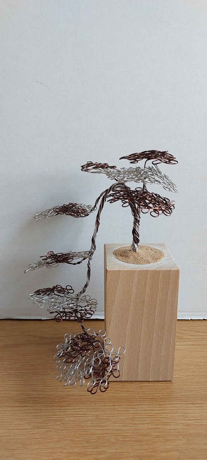 May include: A wire sculpture of a tree with silver and copper wire branches. The tree is on a wooden base.
