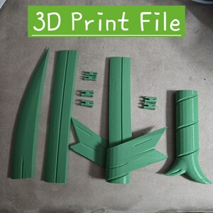 Op de afbeelding: Een verzameling groene 3D-geprinte onderdelen, waaronder lange, platte stukken, bladvormige elementen en kleine verbindingscomponenten. De tekst "3D Print File" wordt weergegeven in een groen rechthoek bovenaan de afbeelding.