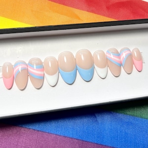 May include: A set of oval-shaped false nails. The nails feature a nude base with various designs, including a pink tip, a white tip, and a light blue tip. Some nails have a design with pink, white, and light blue stripes.