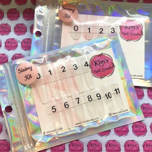 May include: A clear plastic sizing kit for nails, with numbers 0-11 printed on each size. The kit is packaged in a holographic bag with the words "Sizing Kit" and "Kim's Nail Studio" printed on it.