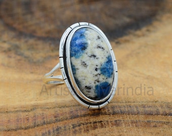 May include: A silver ring with an oval-shaped blue and white gemstone set in a silver bezel. The ring has a textured band.