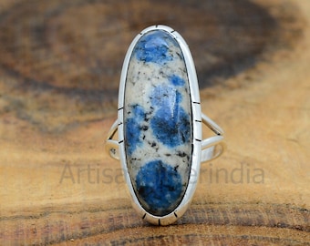 May include: A silver ring with a blue and white oval gemstone. The ring has a simple design with a smooth band and a bezel setting for the stone.