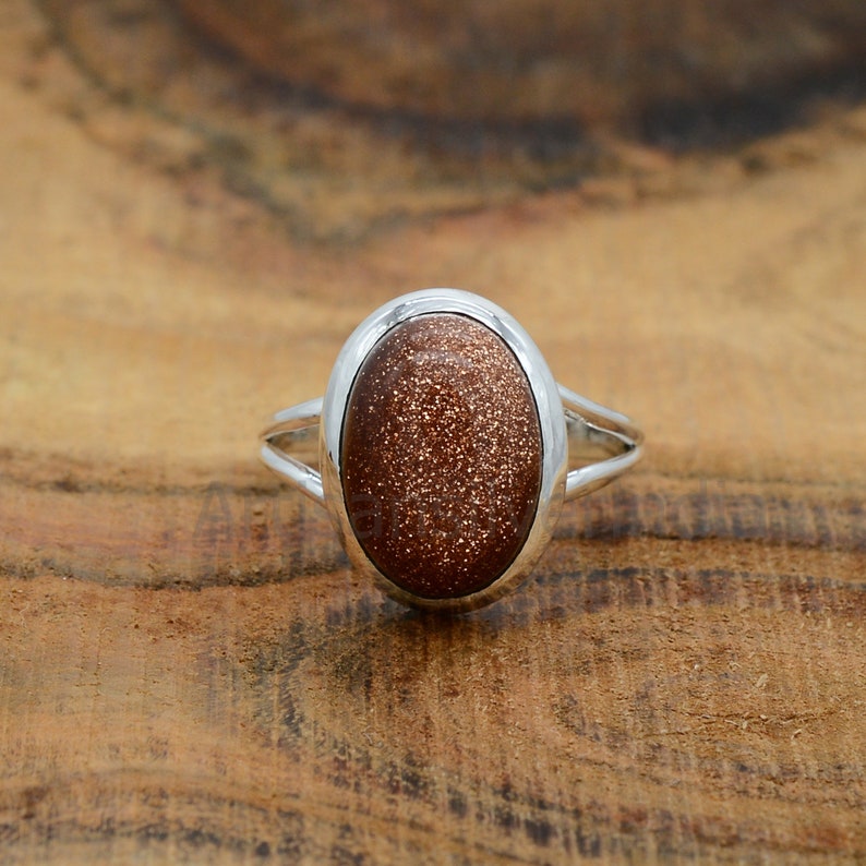 May include: A silver ring with a brown oval-shaped sunstone gemstone.