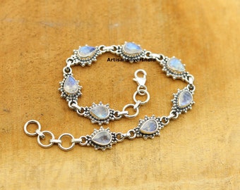 May include: A silver bracelet with a chain link design and teardrop-shaped moonstone gemstones. The bracelet has a lobster clasp closure.
