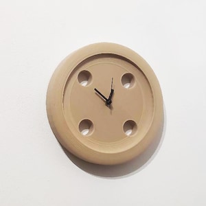 May include: A beige round wall clock with black hands and four holes around the edge.