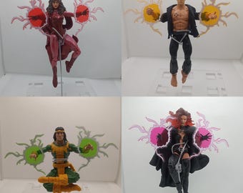 May include: Four action figures of comic book characters. The figures are in various poses, each with energy effects emanating from their hands. The figures are wearing costumes in shades of red, black, green, and yellow. The figures are on clear plastic stands.