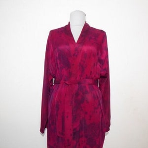 May include: A long, burgundy robe with a tie belt and a tie-dye pattern. The robe is made of a silky material.