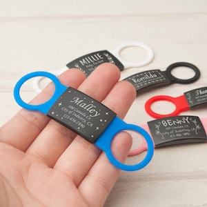 May include: A blue and black personalized pet ID tag with the name "Malley" engraved on it. The tag has a phone number and address engraved on it. The tag is attached to a blue silicone loop.