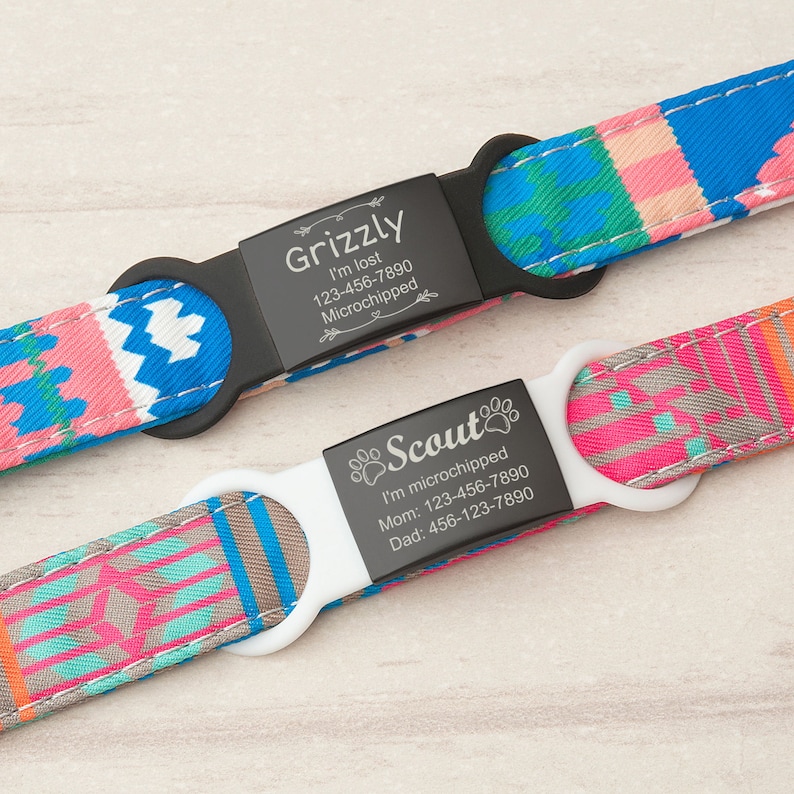 May include: Two dog collars with personalized engraved black metal tags. The collars are blue, pink, and gray with a geometric pattern. The top tag reads "Grizzly I'm lost 123-456-7890 Microchipped". The bottom tag reads "Scout I'm microchipped Mom: 123-456-7890 Dad: 456-123-7890".