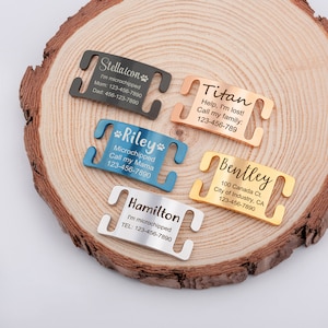 May include: Five different dog collar ID tags with engraved text. The tags are made of metal and come in silver, gold, rose gold, and blue. The text on the tags includes the dog's name, contact information, and a message about being microchipped.