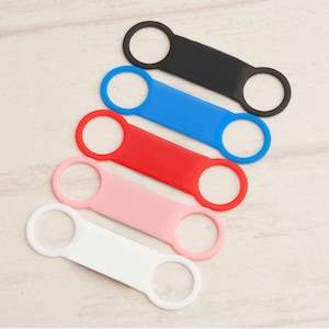 May include: Five silicone loop straps in different colors: black, blue, red, pink, and white. The straps are designed to be used as a phone grip or a keychain.