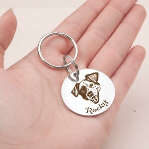 May include: Silver dog tag keychain with a black and white dog portrait and the name "Rocky" engraved on it.