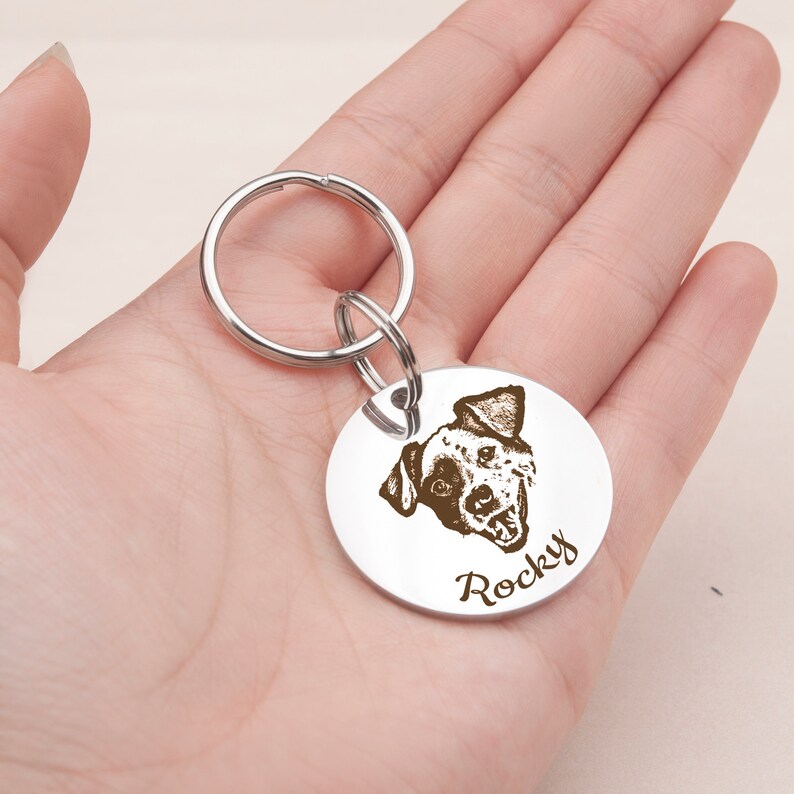 May include: Silver dog tag keychain with a black and white dog portrait and the name "Rocky" engraved on it.