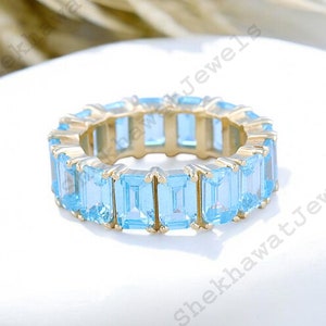 Peut inclure: Une bague en or avec une rangée de pierres précieuses bleu clair de taille émeraude.