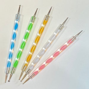 May include: Five nail art tools with different colored handles. The tools have a silver metal tip and a clear plastic handle with a diamond pattern. The handles are blue, green, yellow, white, and pink.
