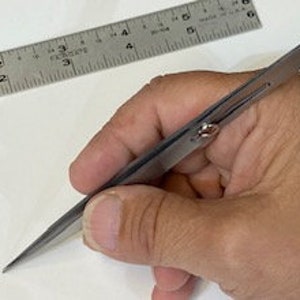 May include: A pair of silver-toned tweezers with a spring-loaded mechanism. The tweezers have a pointed tip and are approximately 4 inches long.
