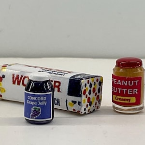 May include: Miniature food items including a loaf of bread with the word "Wonder", a jar of Concord Grape Jelly, and a jar of creamy peanut butter. The bread has colorful dots on the side. The jelly jar has a blue label with a grape illustration.