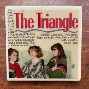 May include: A square ceramic coaster featuring a vintage illustration. The coaster has the title "The Triangle" in red letters. The image depicts three girls standing in front of lockers, with text from a story.
