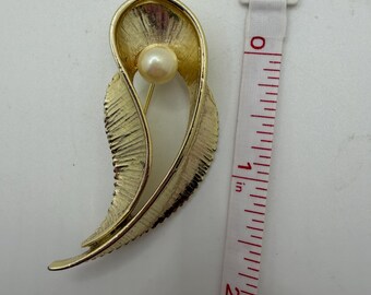 Broche vintage en tono dorado con forma de hoja y detalle de perla sintética.