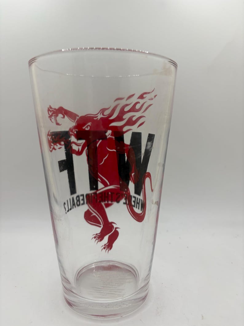 May include: Clear pint glass with a red and black graphic of a dragon-like creature with flames and the letters "FTW". The text "HELL & THE DEVIL'S" is also printed on the glass.