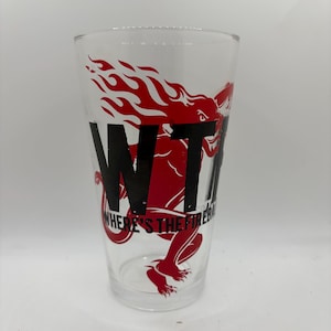 May include: Clear glass pint glass with a red dragon and flame design. The glass features the black text "WTF" and "WHERE'S THE FIRE?". The glass is cylindrical and suitable for beverages.