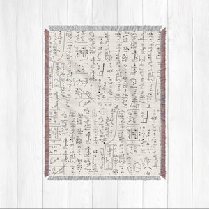 Könnte beinhalten: Eine weiße Decke mit einem schwarz-weißen Muster aus mathematischen Gleichungen und Symbolen. Die Decke hat einen Fransenrand.