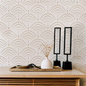 May include: A wooden table with a light wood finish and a decorative tray with two black mirrors, a white vase with dried flowers, and a beaded necklace. The wall behind the table has a white background with a repeating pattern of brown dots and diamonds.