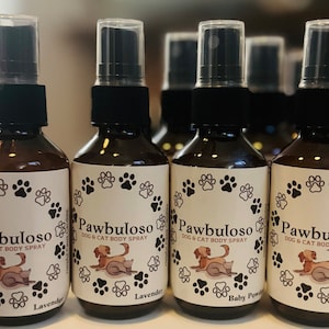 Può includere: Quattro bottiglie di vetro ambrato con spruzzini neri ed etichette bianche. Le etichette hanno un design a forma di impronta di zampa e il testo "Pawbuloso DOG & CAT BODY SPRAY". Due bottiglie hanno il testo "Lavender" e due bottiglie hanno il testo "Baby Powder".