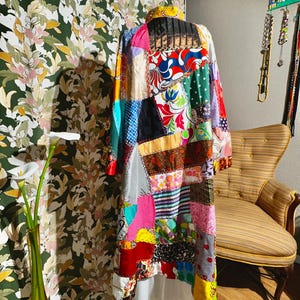 May include: A colorful patchwork coat with a variety of fabrics and patterns, including floral, geometric, and plaid. The coat has a long, flowing silhouette and is made of a soft, comfortable material.