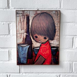 May include: A framed illustration of a young person with brown hair and a red shirt standing next to a bottle and a blue glass. The illustration is signed "Mourman".