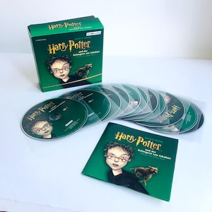 May include: A boxed set of Harry Potter and the Prisoner of Azkaban CDs. The box and CDs are green with the book cover art featuring Harry Potter. The set includes a booklet and multiple CDs in individual sleeves.