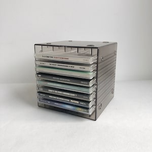 Peut inclure: Un support de rangement pour CD en plastique gris foncé translucide contenant huit boîtiers de disques compacts. La pile comprend des albums de The Last Shadow Puppets, The Velvet Underground & Nico, Madonna, Meat Loaf, Placebo, Oasis, Pulp Fiction et John Martyn.