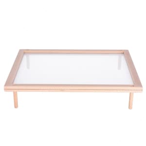 Puede incluir: Una prensa de flores rectangular de madera con una fina pantalla de malla. La prensa tiene cuatro patas de madera y está diseñada para prensar flores y conservar especímenes botánicos. El color natural de la madera le da una estética rústica.