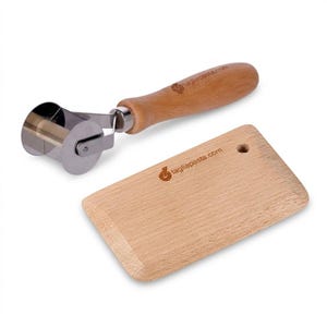 May include: A pasta cutter and a wooden board. The pasta cutter has a stainless steel blade and a wooden handle. The wooden board is rectangular with a small hole and the text taglipasta.com.
