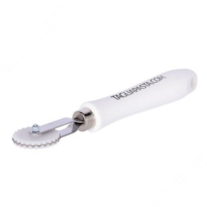 May include: White pasta cutter with a white handle and a silver blade. The handle has the text "TAGLIAPASTA.COM" printed on it.