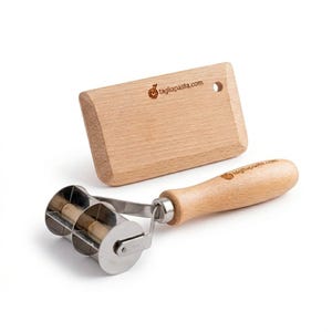 May include: A wooden pasta cutter and a wooden scraper are displayed on a white background. The pasta cutter has a stainless steel roller with a wooden handle. The scraper has a rectangular shape with a hole and the text tagliapasta.com.