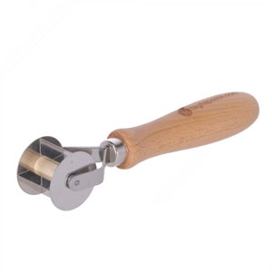 May include: A silver pastry roller with a wooden handle. The roller has a decorative design and is used for making pastries.