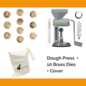 May include: A gray metal dough press with a white plastic handle and a white plastic cover. The press is accompanied by 10 brass dies with different shapes and a white canvas bag with the text "www.tagliapaste.com". The text "Dough Press + 10 Brass Dies + Cover" is written below the press.