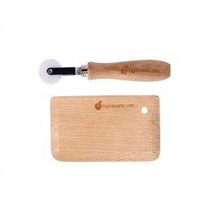 May include: A wooden pasta cutter with a white, toothed wheel and a wooden handle, next to a rectangular wooden cutting board. The text "tagliapasta.com" is printed on both items.