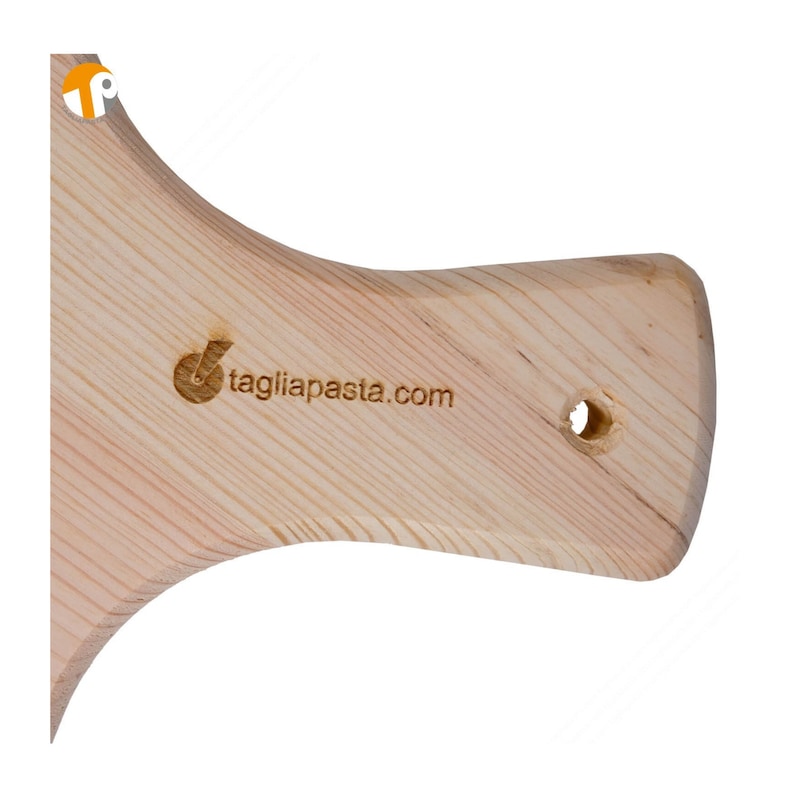 May include: A light-colored wooden pasta cutting board with a handle. The handle has a hole for hanging and the text "tagliapasta.com" is visible. The wood grain is visible.