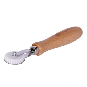 May include: A white plastic pastry wheel with a wooden handle. The handle is labeled "Le Creuset".