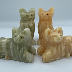 May include: Four hand-carved onyx cat figurines. Two are light green and two are light orange. The cats are in various poses, including sitting and lying down.