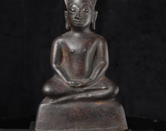 May include: A bronze Buddha statue seated in a meditative pose, hands in lap. The statue has a pointed headdress and is mounted on a black rectangular base. The figure has a serene expression. The statue is made of bronze.